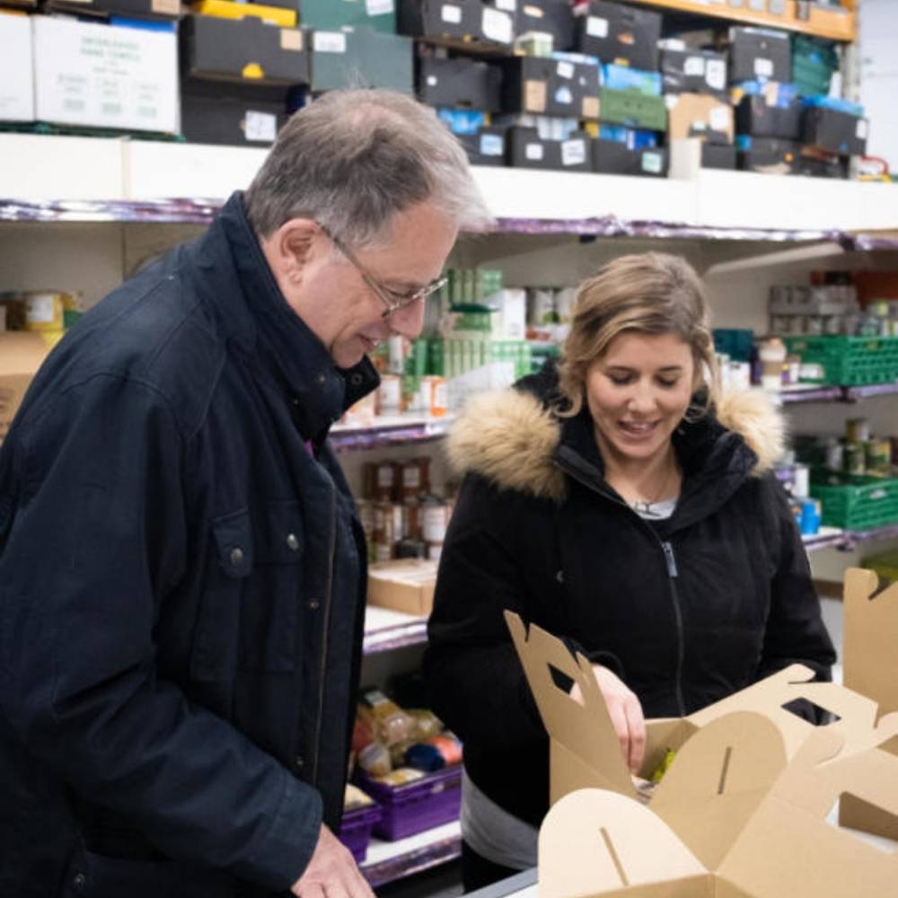 Bishop Steven standing with a St Marks meals volunteer looking at the contents of meal boxes